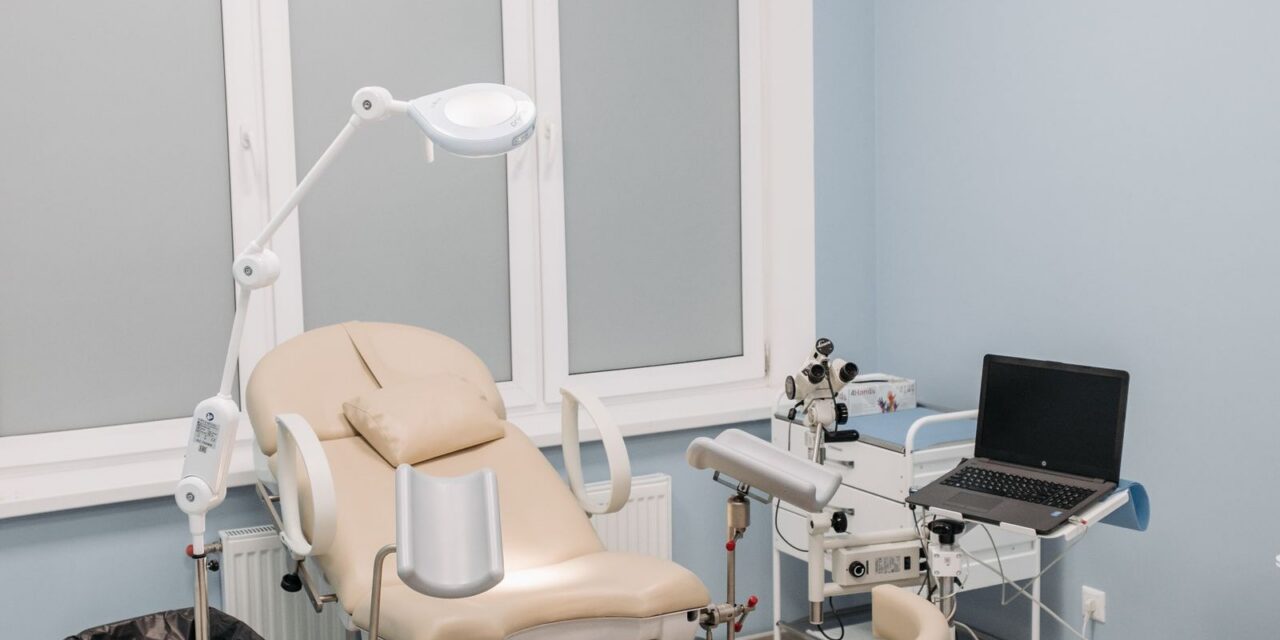 Clean modern clinic examination room with an examination chair and adjustable procedure light