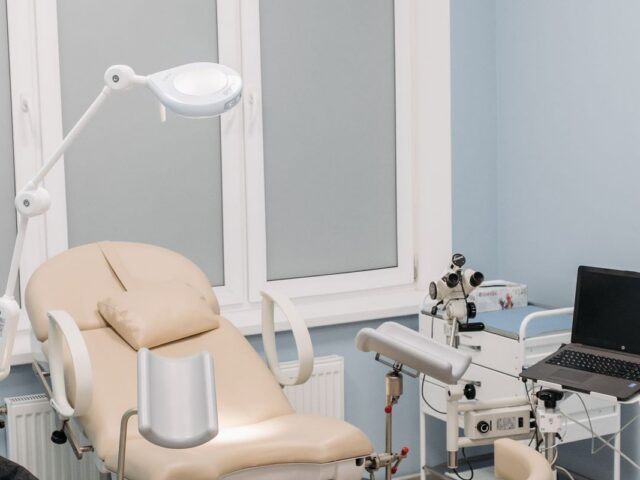 Clean modern clinic examination room with an examination chair and adjustable procedure light